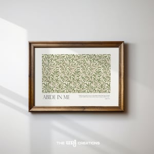 Puede incluir: Una impresión enmarcada con un patrón botánico verde y beige. El texto "ABIDE IN ME" está en la parte inferior izquierda, con un versículo bíblico a la derecha. El marco es de color marrón oscuro.