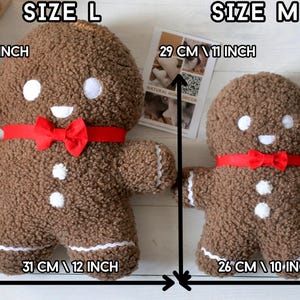 May include: Two brown textured plush gingerbread figures with white circular eyes and buttons, and a red bow tie. The large figure measures 36 cm by 31 cm, and the medium figure measures 29 cm by 26 cm, as indicated by the text in the image.