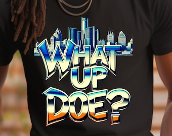 Könnte beinhalten: Ein schwarzes T-Shirt mit einer Grafik einer Skyline und dem Text "WHAT UP DOE?" in einer metallischen blauen und orangenen Schrift.