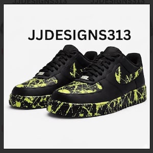 May include: Black sneakers with neon yellow paint splatter design. The shoes have black laces, a black Nike swoosh, and the text "JJDESIGNS313" at the top. The soles and toe area are covered in the neon yellow splatter.