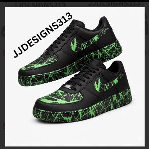 May include: Pair of black sneakers with neon green splatter paint design on the soles and accents. The Nike swoosh is neon green. The text "JJDESSIGNS313" is printed on the upper left side of the image.