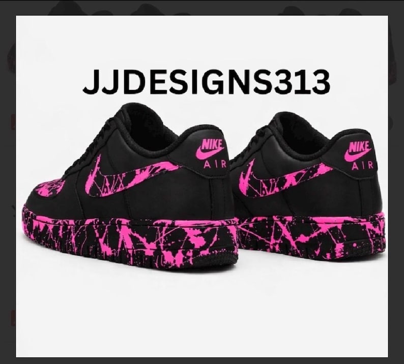 May include: Black Nike Air Force 1 sneakers with pink splatter design on the soles, swoosh, and accents. The text "JJDESIGNS313" is at the top of the image. The Nike logo is visible on the heel.