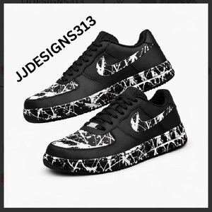 May include: Pair of black and white sneakers with a splatter paint design. The shoes feature a white Nike swoosh and black laces. The text "JJDESIGNS313" is visible in the upper left corner.