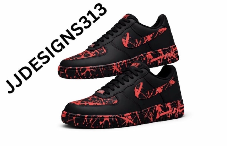 May include: Pair of black sneakers with red splatter design on the soles, toe box, and Nike swoosh. The shoes have black laces and a black tongue. The text "JJDESIGNS313" is in the upper left corner.