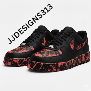 May include: Pair of black sneakers with red splatter paint design. The shoes have black laces, a black sole, and a red Nike swoosh. The text "JJDESSIGNS313" is printed on the upper left.