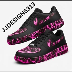 May include: Pair of black sneakers with pink splatter design accents. The shoes feature a pink Nike swoosh and a pink splatter pattern on the toe and sole. The text "JJDESSIGNS313" is visible.