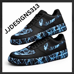 May include: Black sneakers with blue splatter paint design. The Nike swoosh logo is visible on the side. The text "JJDESIGNS313" is printed on the side of the shoe.