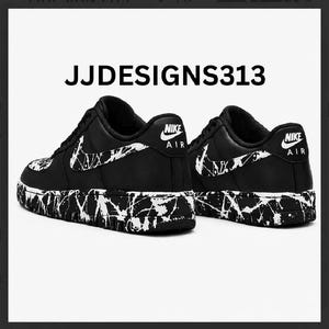 May include: Black and white Nike Air Force 1 sneakers with a splatter paint design on the soles and Nike logo on the heel. The text "JJDESIGNS313" is displayed above the shoes.