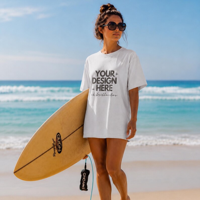 May include: A white short-sleeved t-shirt featuring the dark gray text "YOUR DESIGN HERE" with small star icons and the cursive word "brillantes" underneath, paired with a light brown surfboard with a black leash and dark sunglasses.