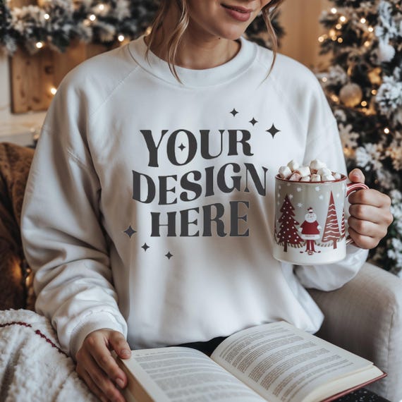 White Customizable Sweatshirt Mockup with Christmas Mug and Open Book-Cozy Winter Holiday Background,Perfect for Personalized Clothing Shops