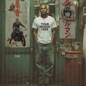 Puede incluir: Una persona con una camiseta blanca con el texto "YOUR DESIGN HERE" y vaqueros azules. La persona está de pie frente a una puerta con carteles japoneses. La camiseta tiene rayas verticales.