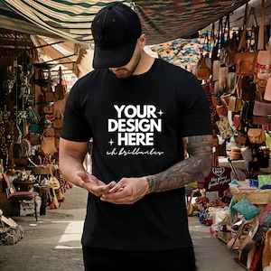 Puede incluir: Una camiseta negra con el texto "YOUR DESIGN HERE + eh brillantes" impreso en blanco en la parte delantera.