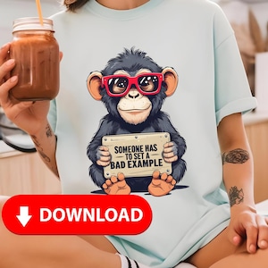 Könnte beinhalten: Hellblaues T-Shirt mit einem Cartoon-Schimpansen, der eine rote Sonnenbrille trägt und ein Schild mit der Aufschrift "SOMEONE HAS TO SET A BAD EXAMPLE" hält. Der Schimpanse ist schwarz und hat braune Ohren und Füße.