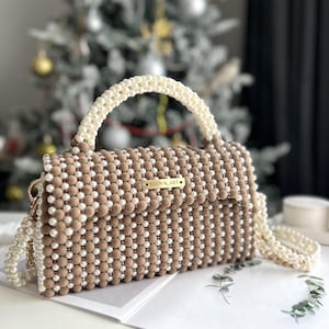Lujoso bolso adornado con cuentas tipo perla y pequeños detalles de cristal.