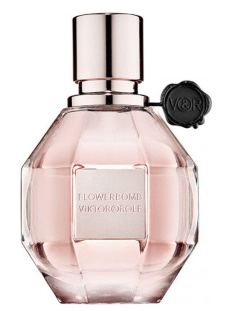 May include: A clear glass bottle of Flowerbomb perfume by Viktor & Rolf. The bottle is shaped like a grenade and has a pink liquid inside. The bottle has a silver cap and a black seal with the letters V&R on it.