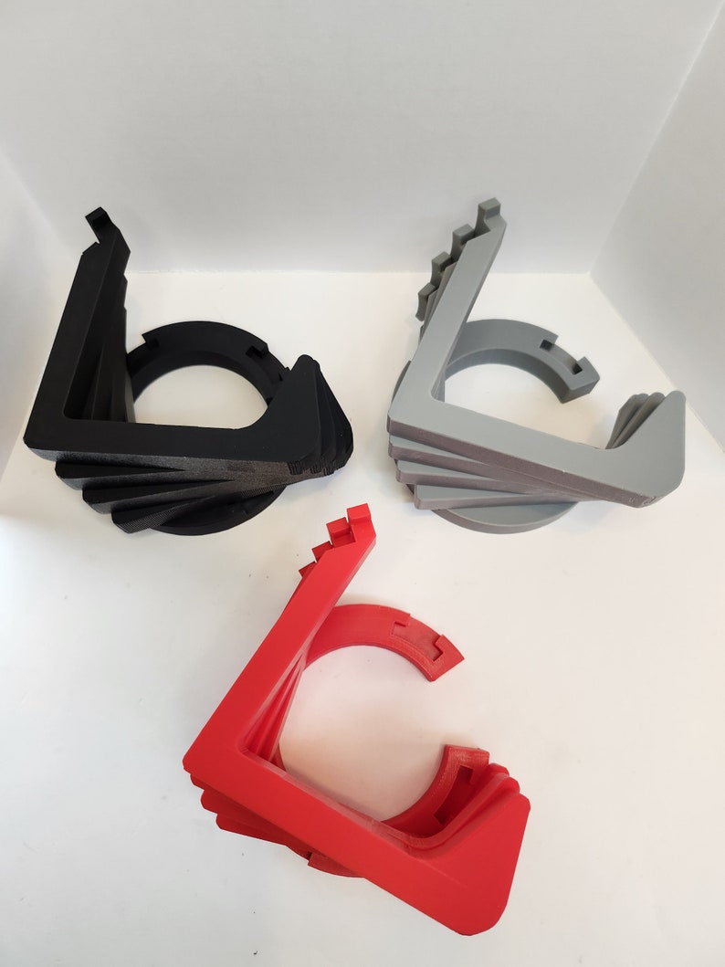May include: Three 3D printed stands in black, gray, and red. Each stand is made of multiple layers and has a circular opening in the center.