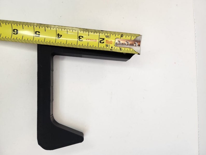 May include: Black plastic corner bracket with a measurement of 2 inches. The bracket is designed to be used for joining two pieces of wood or other materials at a 90-degree angle.