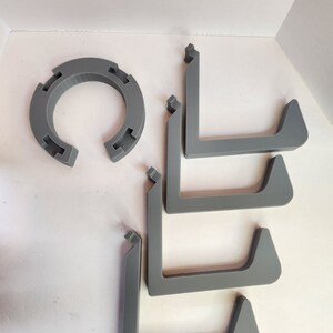 May include: Five gray plastic L-shaped shelf brackets and a gray plastic ring.