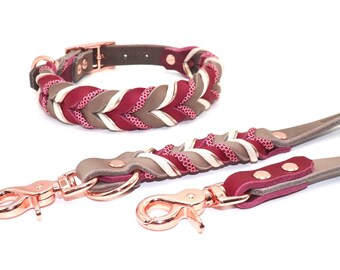 May include: A dog collar and leash set in shades of burgundy, taupe, and cream. The collar and leash feature a braided design with rose gold hardware. The set is made of leather and fabric.