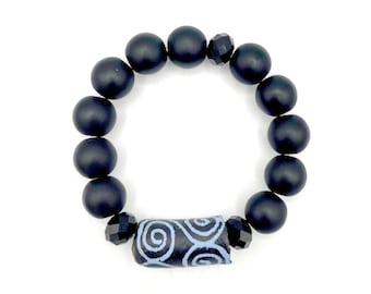 May include: Black beaded bracelet with a blue and black patterned bead in the center.