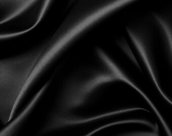Pode incluir: Um tecido de cetim preto liso com dobras suaves e fluidas. O tecido é drapeado e dobrado para criar um fundo luxuoso e elegante.