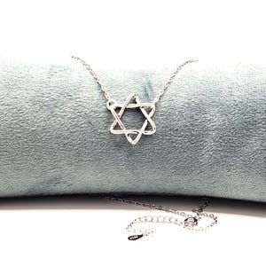 Puede incluir: Un collar de cadena de plata con un delicado colgante de Estrella de David entrelazado.