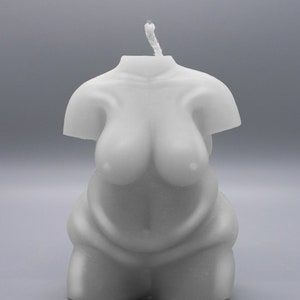 May include: A white candle shaped like a human torso. The candle has a simple design and is made of a smooth, white wax.