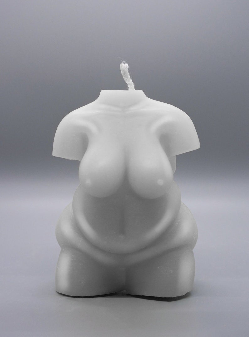 May include: A white candle shaped like a human torso. The candle has a simple design and is made of a smooth, white wax.