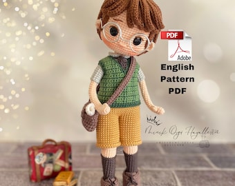 Könnte beinhalten: Gehäkelte Puppe eines jungen Menschen mit Brille, grüner Weste, gelben Shorts und braunen Schuhen. Die Puppe hat eine braune Tasche und Haare. Das Bild enthält den Text "Adobe English Pattern PDF".