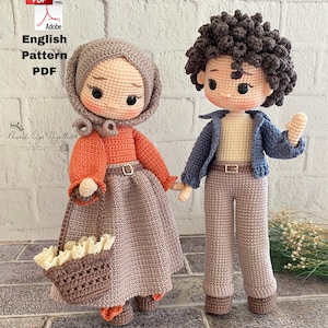 May include: Two crocheted dolls, a couple, stand together. The female doll wears an orange top, a grey skirt, and a head covering. The male doll wears a blue jacket and beige trousers. They are holding hands. The image includes text that says "English Pattern PDF".