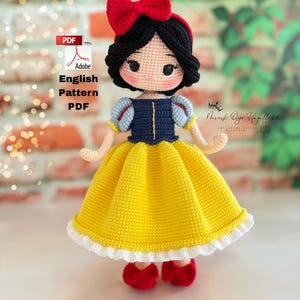 May include: Crocheted doll of a princess with black hair, a red bow, and a yellow dress. The doll has a blue bodice with white and blue sleeves, red shoes, and a white lace trim on the dress. The image includes text that says "English Pattern PDF".