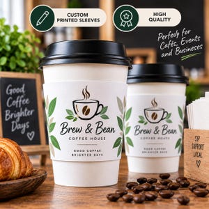 May include: Two white paper coffee cups with black lids, each featuring a custom sleeve printed with the text Brew & Bean Coffee House, Good Coffee Brighter Days, and a graphic of a steaming coffee cup surrounded by green and brown leaves.