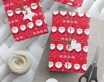 May include: Two red gift boxes wrapped in Christmas paper with a Santa Claus pattern and the words "Ho Ho Ho" printed on them. The boxes are tied with twine and have white paper tags attached.
