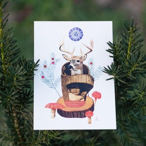 May include: A whimsical art print featuring a deer with large antlers, a child, and red mushrooms. The artwork is set against a white background with blue accents and is surrounded by green foliage. The overall theme is nature and fantasy.