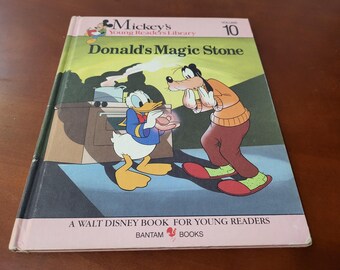 May include: A vintage copy of "Donald's Magic Stone," Volume 10 in the Mickey's Young Readers Library series. The cover features Donald Duck and Goofy in a colorful illustration. Published by Bantam Books, this Walt Disney book is a children's story.