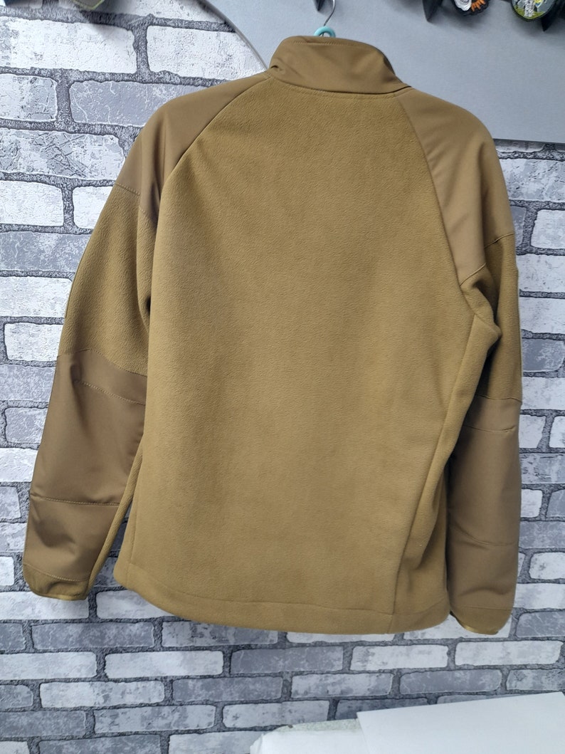May include: A brown fleece jacket with a zip fastening and a stand-up collar. The jacket has a brown and tan colour block design.