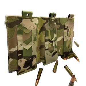 May include: A camouflage-patterned tactical magazine pouch with three compartments. The pouch is made of durable fabric and features a series of decorative cutouts. Several bullets are scattered around the pouch, with brass-colored tips and green casings.