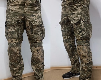 Könnte beinhalten: Tarnfarbene Cargohose mit mehreren Taschen und verstärkten Kniepolstern. Die Hose hat ein digitales Tarnmuster in Grün, Braun und Beige. Die Hose hat eine lockere Passform und ist auf Langlebigkeit und Funktionalität ausgelegt.