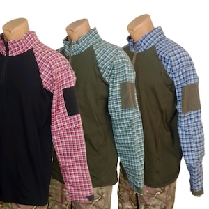 Pode incluir: Três camisas de manga comprida com fecho de correr no colarinho. A primeira é preta com mangas xadrez vermelhas, a segunda é verde-azeitona com mangas xadrez verdes e a terceira é verde-azeitona com mangas xadrez azuis. Cada manga tem um remendo.