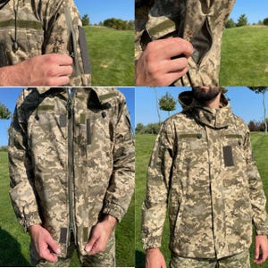 May include: A camouflage jacket in shades of green, brown, and tan. The jacket features a full-length zipper, multiple pockets, and a hood. Details include Velcro patches and zippered arm vents. The jacket is designed for outdoor wear.