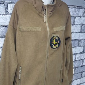 May include: A tan fleece jacket with a zip fastening and a patch on the left breast that says "MILF HUNTER".