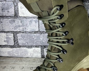 May include: Green leather hiking boots with black laces and a black buckle. The boots have a thick rubber sole with a tread pattern.