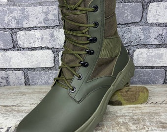May include: Olive green combat boot with a high-top design. The boot features a lace-up closure, a durable sole, and a combination of leather and fabric materials. The boot is designed for rugged outdoor use.