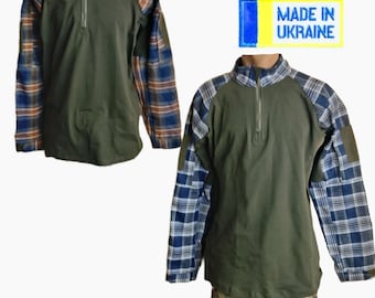 May include: A long-sleeve quarter-zip shirt featuring a solid olive green torso and blue and white plaid sleeves with a high collar. A rectangular yellow and blue patch with the text MADE IN UKRAINE is positioned above the shirt.