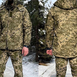May include: A two-piece camouflage uniform in shades of green, brown, and tan. The jacket has a hood and multiple pockets. The trousers match the jacket's pattern. The outfit is designed for cold weather and outdoor use.