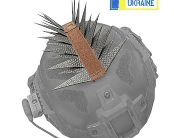 May include: A gray tactical helmet with a brown strap and spiky attachments. The helmet has a headset and the text "MADE IN UKRAINE" on a yellow and blue patch.