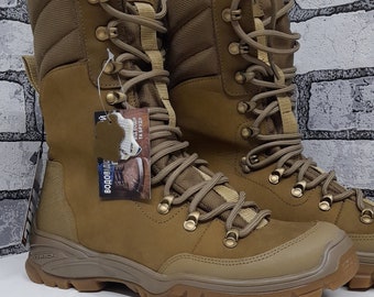 May include: A pair of tan tactical boots featuring a high-top design, reinforced toe caps, and a rugged lugged outsole. The boots have a lace-up closure with metal eyelets and hooks, padded collars, and a tag attached to the side.