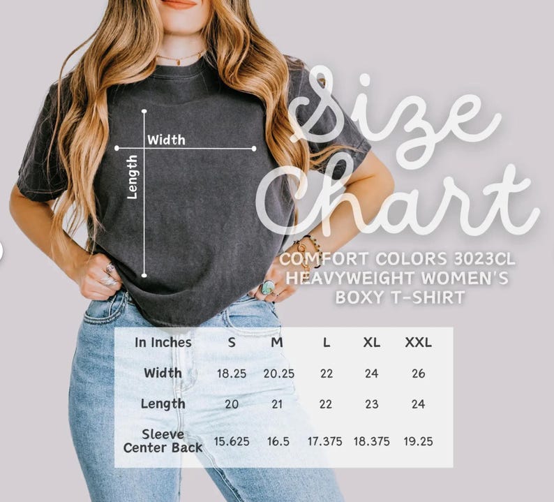 May include: A size chart for a Comfort Colors 3023CL heavyweight boxy t-shirt. The chart shows measurements in inches for width, length, and sleeve center back for sizes S, M, L, XL, and XXL. The t-shirt is a dark gray color.