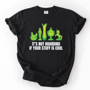May include: Black t-shirt with the text "IT'S NOT HOARDING IF YOUR STUFF IS COOL." The shirt features a green graphic of a chicken, a statue, a vase, a covered dish, and a unicorn.
