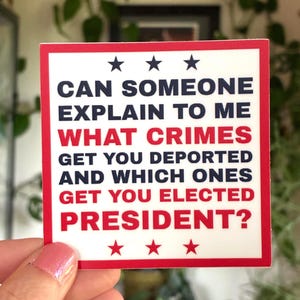 Op de afbeelding: Een witte sticker met een rode rand en de tekst: "CAN SOMEONE EXPLAIN TO ME WHAT CRIMES GET YOU DEPORTED AND WHICH ONES GET YOU ELECTED PRESIDENT?" De tekst is in zwart en rood met drie sterren aan de boven- en onderkant.